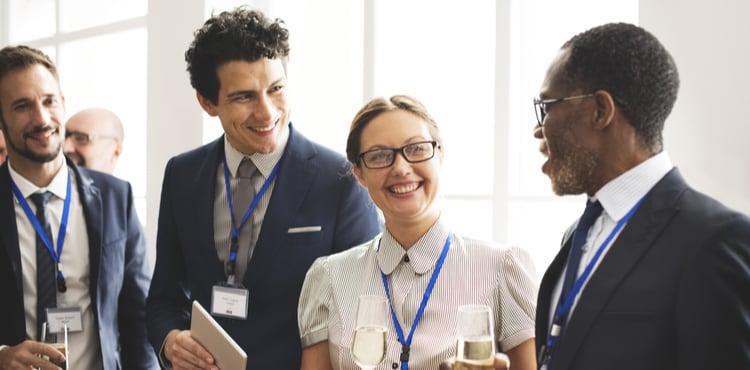 A group of people converse at a work event. A group of people converse at a work event.